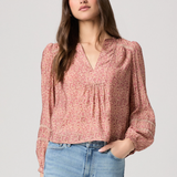 Woman wearing a pink floral blouse and blue jeans on a light gray background