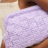 Person holding a purple woven clutch bag