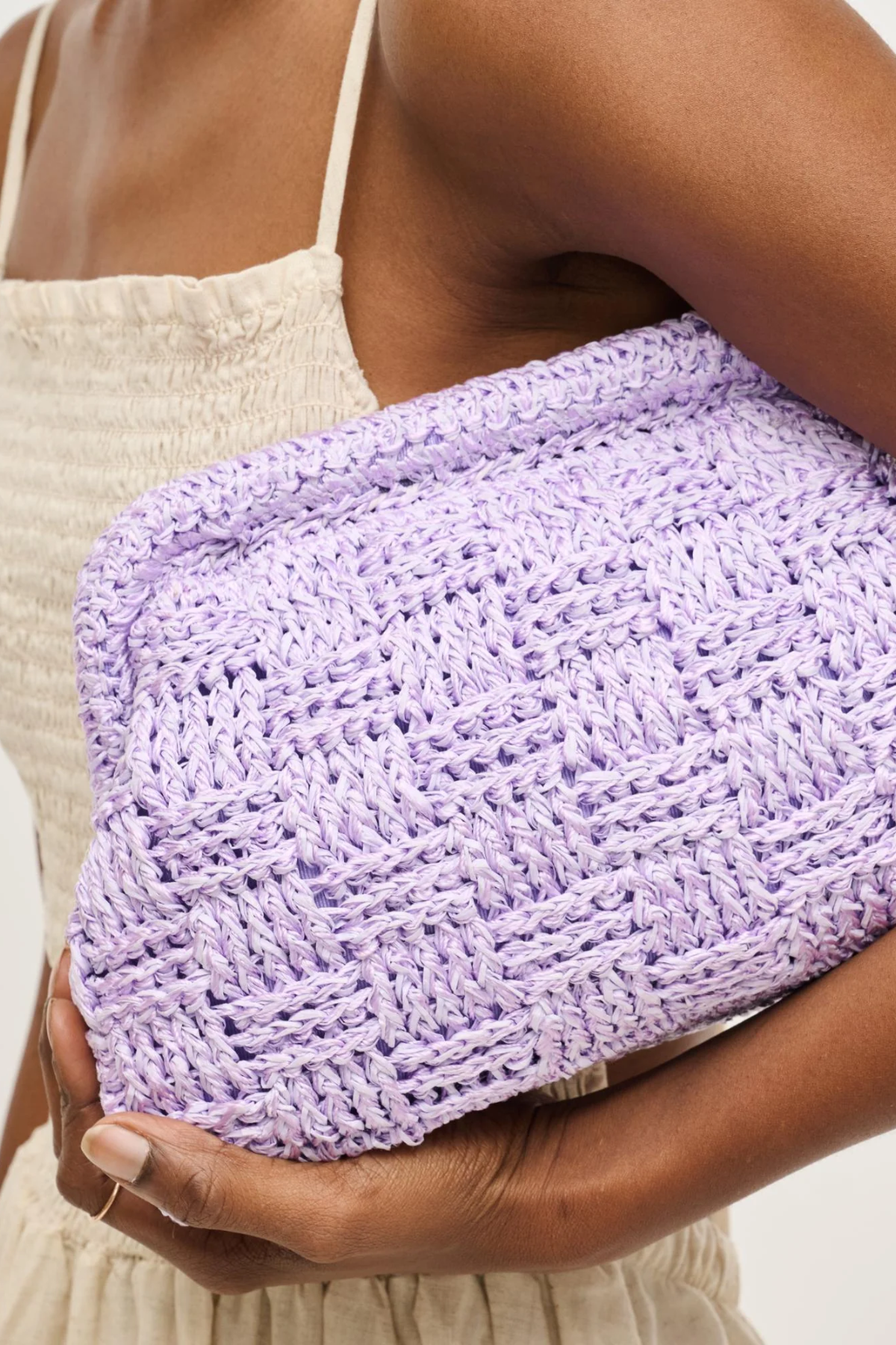 Person holding a purple woven clutch bag