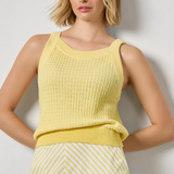 Woman wearing a yellow sleeveless top and skirt against a plain background
