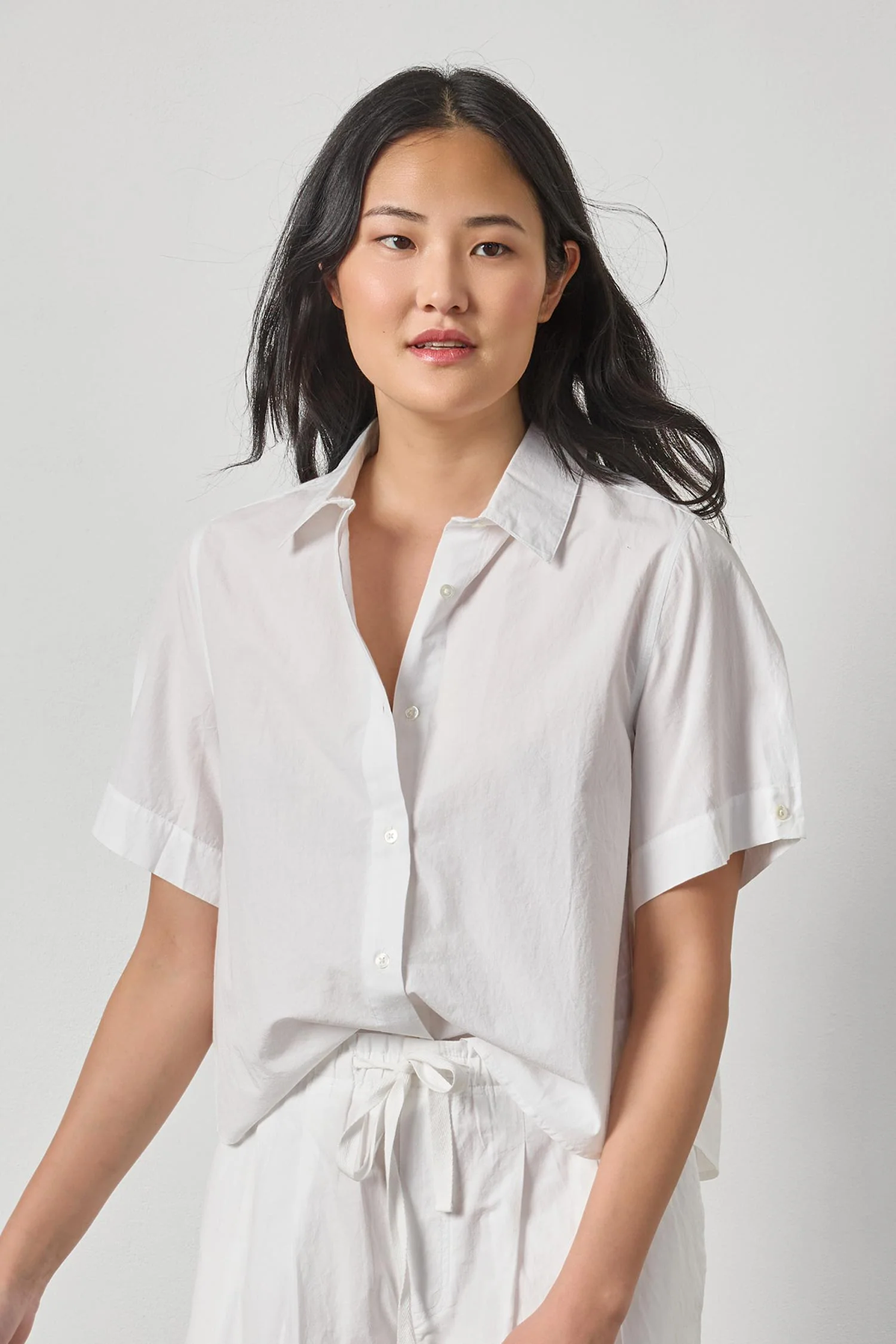 Woman wearing a white shirt against a plain background