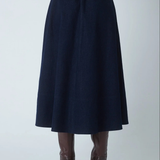 A dark navy blue A-line midi skirt with an elastic waistband, shown on a model from the back wearing brown high-heeled boots against a light gray studio background.
