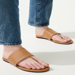 Tan sandals worn with blue jeans on a light background