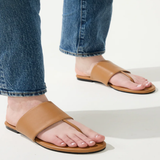 Tan sandals worn with blue jeans on a light background