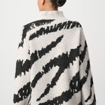 Person wearing a black and white patterned jacket on a white background