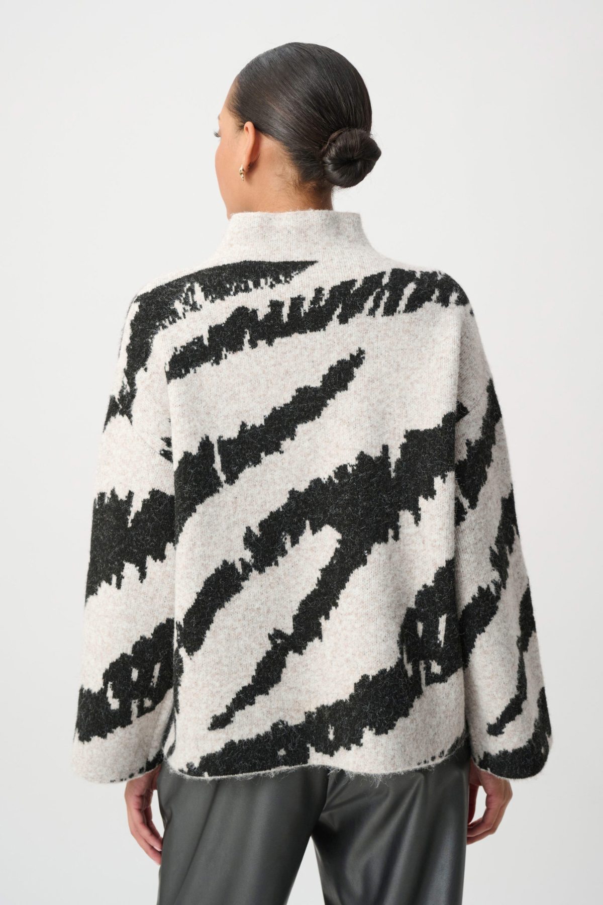Person wearing a black and white patterned jacket on a white background