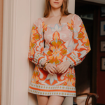 Woman wearing a colorful floral dress standing indoors.