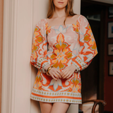 Woman wearing a colorful floral dress standing indoors.