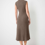 A woman stands with her back to the camera wearing a sleeveless, ribbed knit midi dress in a taupe-brown color, paired with black pointed-toe flats, against a plain white wall and light concrete floor.