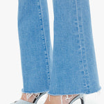 Close-up of blue jeans and high-heeled shoes on a white background