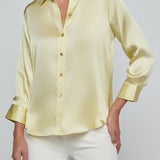 Light yellow blouse with long sleeves and white pants on a plain background