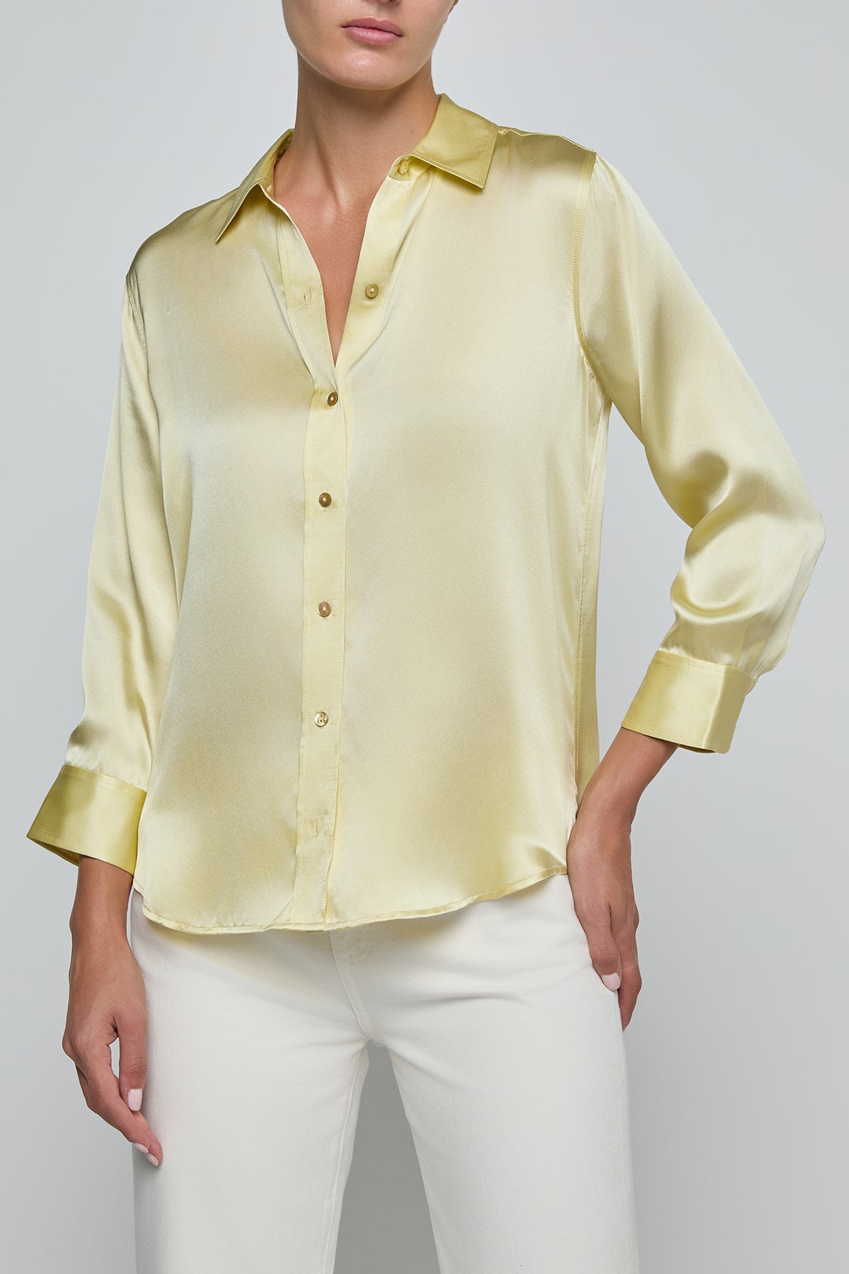 Light yellow blouse with long sleeves and white pants on a plain background