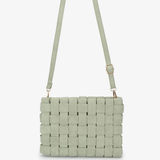 A light sage green woven leather shoulder bag with a matching adjustable shoulder strap and gold-tone hardware, shown against a plain white background.