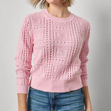 Woman wearing a pink knitted sweater and blue jeans on a gray background
