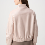 Woman wearing a beige jacket on a light gray background