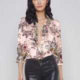 Woman wearing a floral blouse and black pants on a gray background