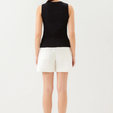 Woman wearing a black sleeveless top and white shorts on a white background