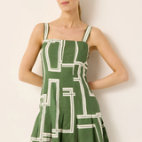 Woman wearing a green dress with white geometric patterns against a plain background