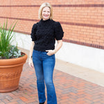 Knit sweater with puff sleeves and pom pom texture, styled with denim.