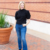 Knit sweater with puff sleeves and pom pom texture, styled with denim.