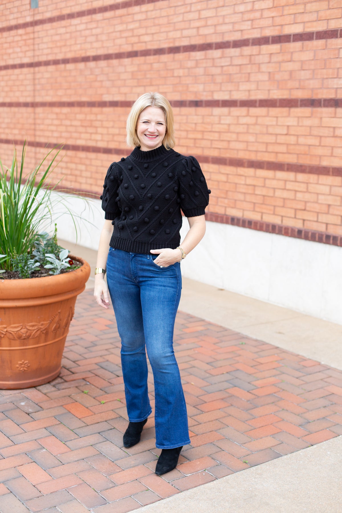 Knit sweater with puff sleeves and pom pom texture, styled with denim.