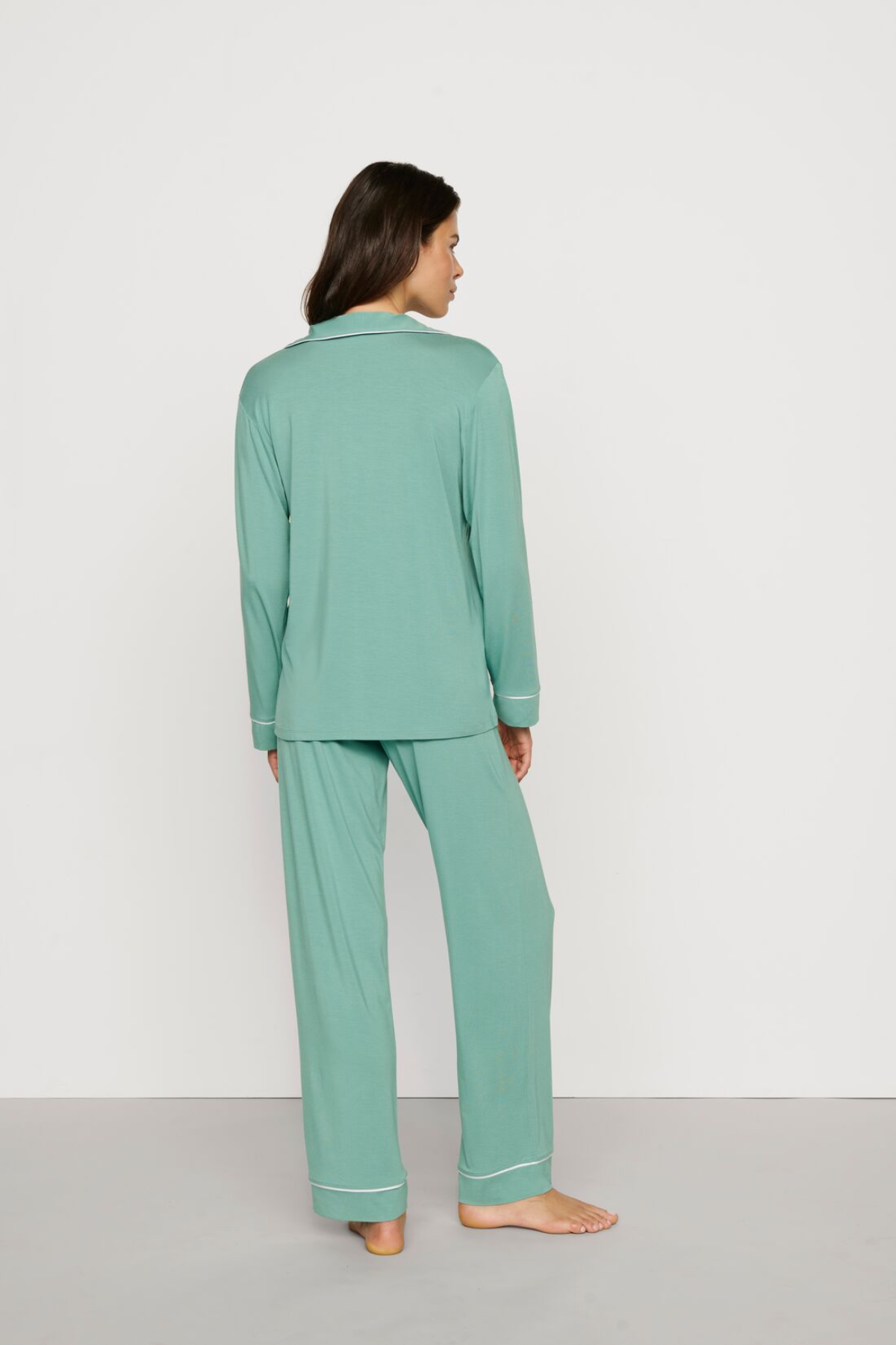 Person wearing a teal pajama set on a plain background
