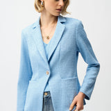 Woman wearing a light blue blazer and jeans on a plain background
