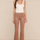 Model wearing white tank top and tan jeans on ivory background.