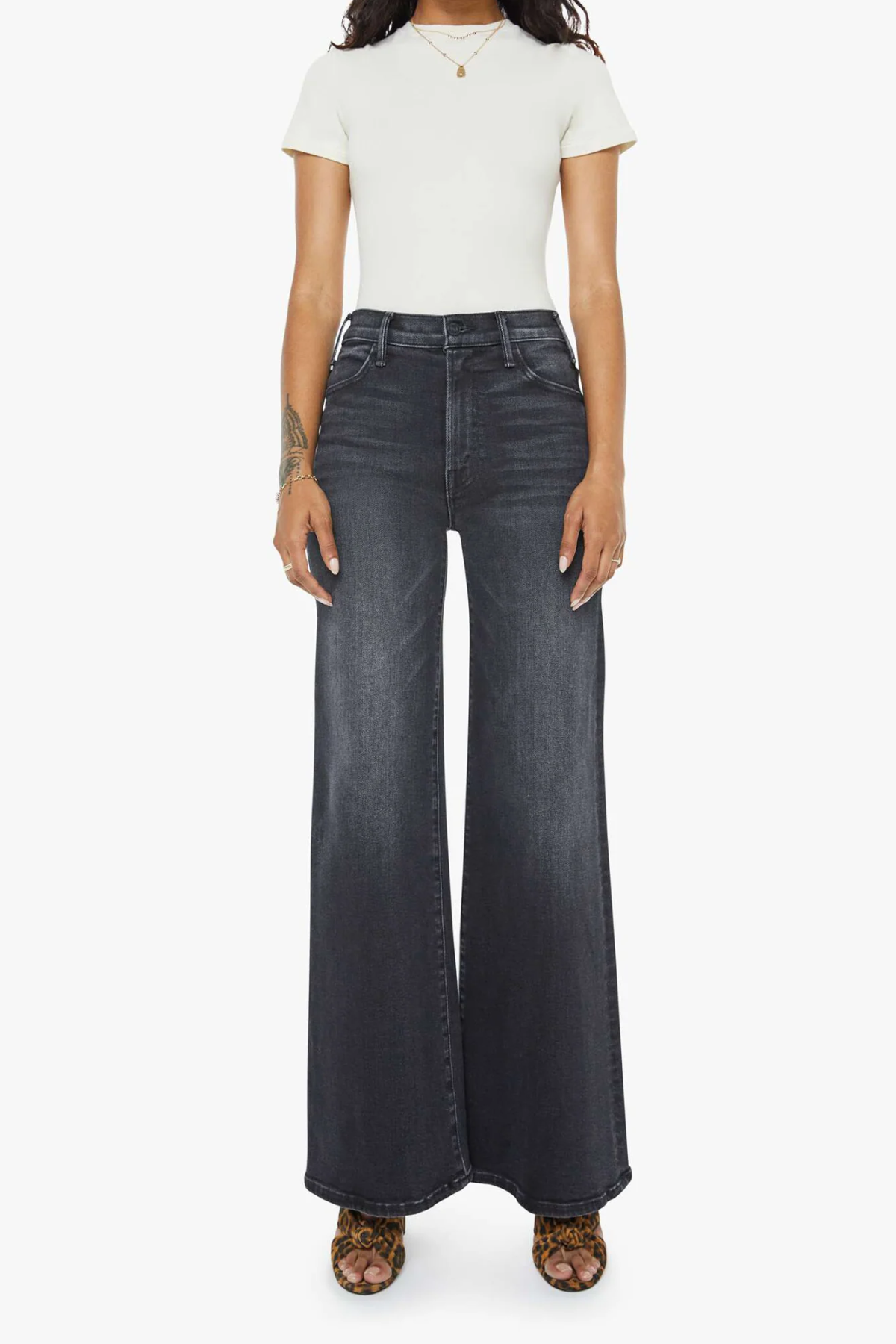 Person wearing black flared jeans and a white t-shirt on a white background