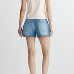 Person wearing a white t-shirt and blue denim shorts on a plain background