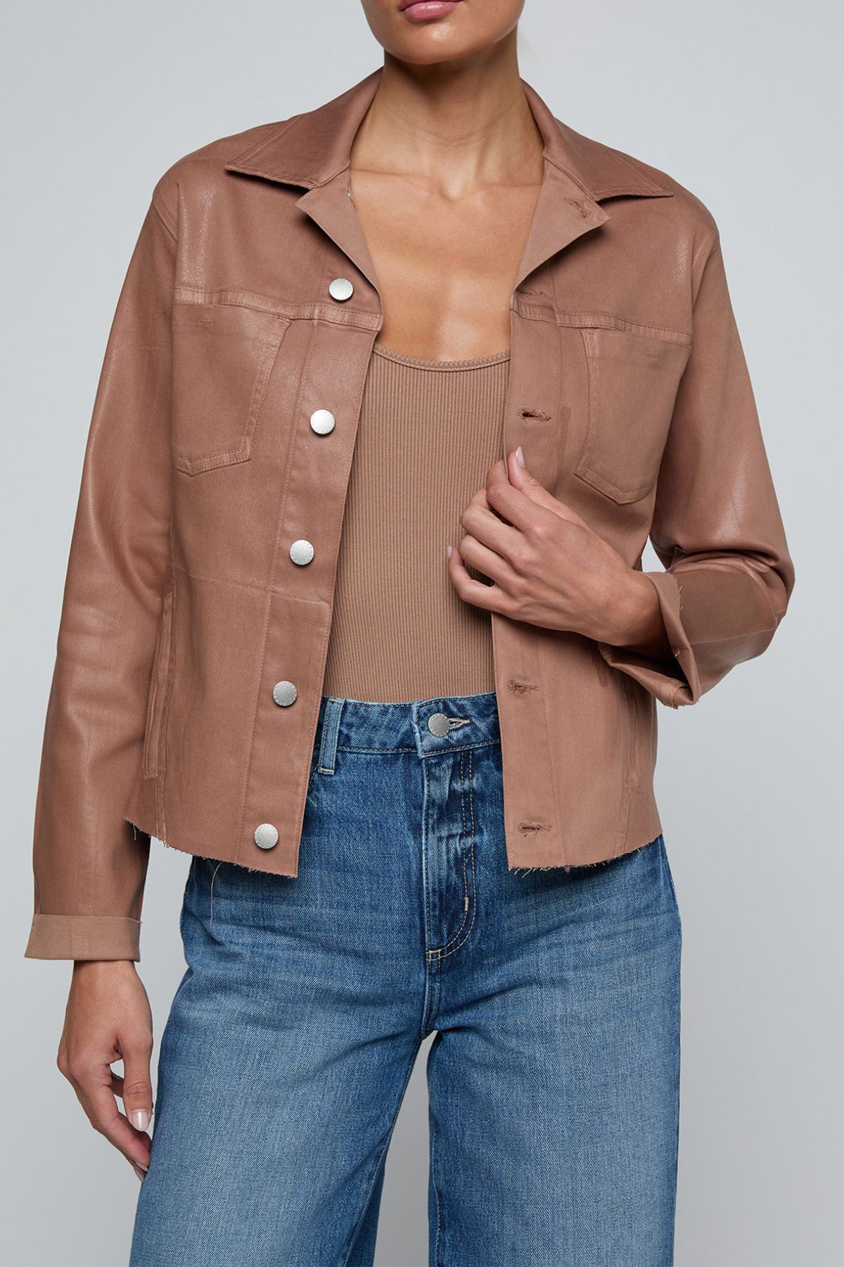 Model wearing a light-wash slim-fit denim jacket with raw hem detailing and a button-front design.