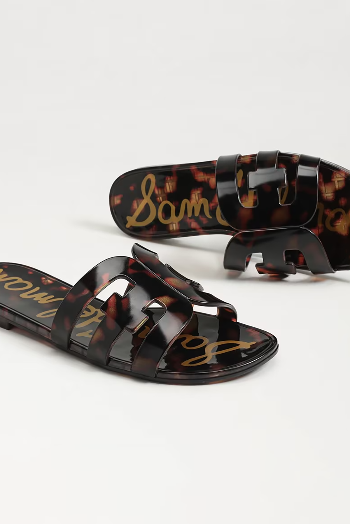 Tortoiseshell sandals with brand name on a light gray background