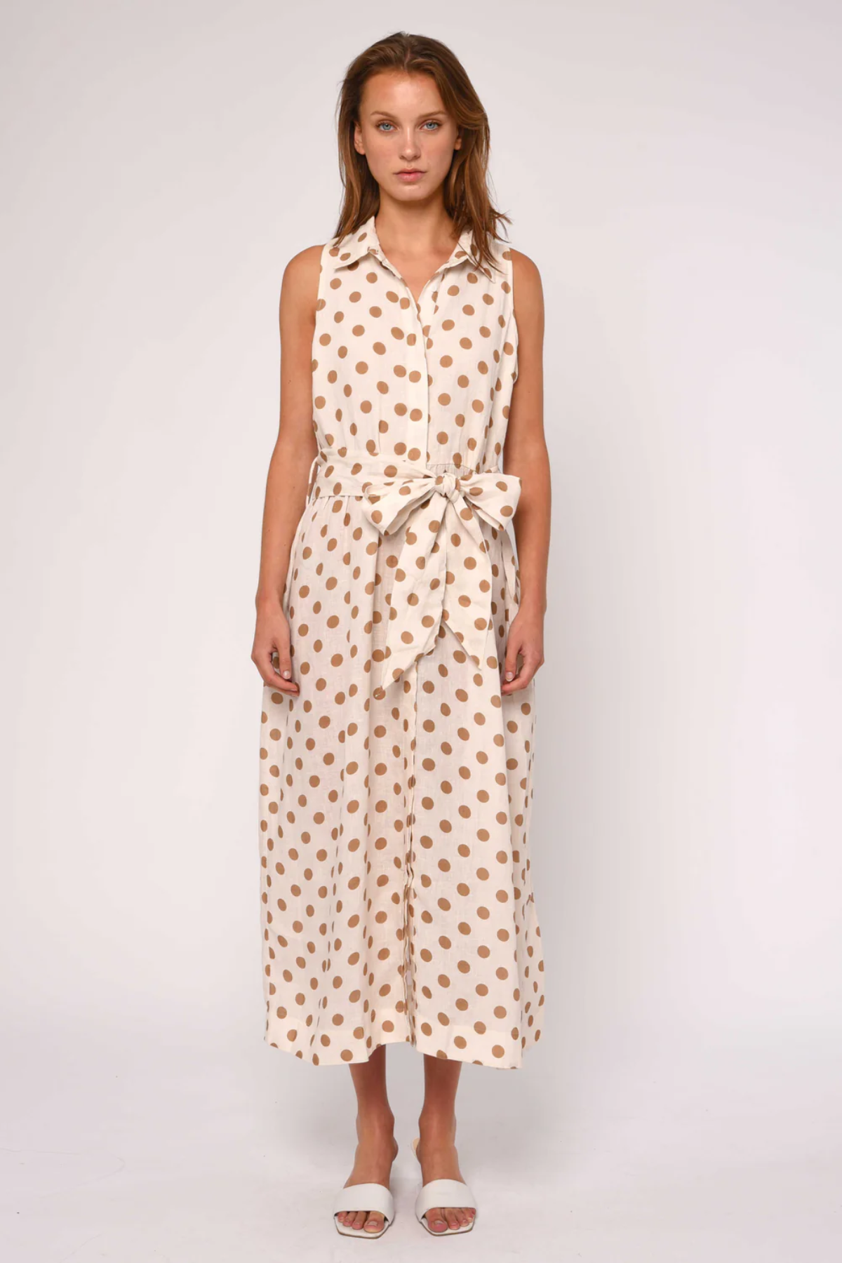 Woman wearing a sleeveless dress with a polka dot pattern on a white background