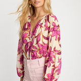 side view of woman in pink printed blouse on white background 