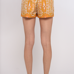 Model wearing tailored tan shorts with a clean, relaxed silhouette.
