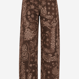 A pair of wide-leg brown jeans with a detailed paisley and floral pattern in a lighter tan or beige tone, shown against a plain white background.