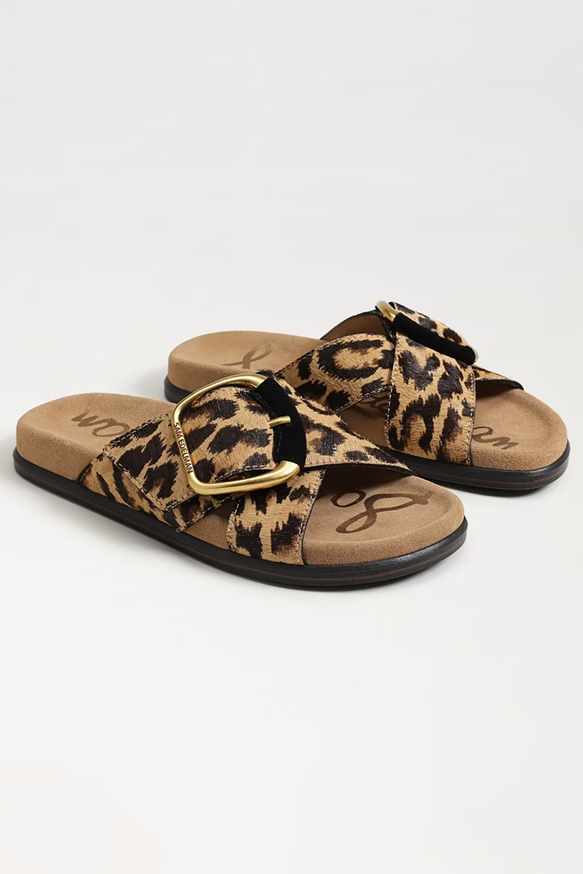 Pair of leopard print sandals with a gold buckle on a light gray background