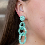 Close-up of a person wearing turquoise beaded earrings.