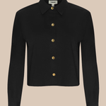 A black long-sleeve collared shirt jacket with gold buttons, displayed on a solid beige background.