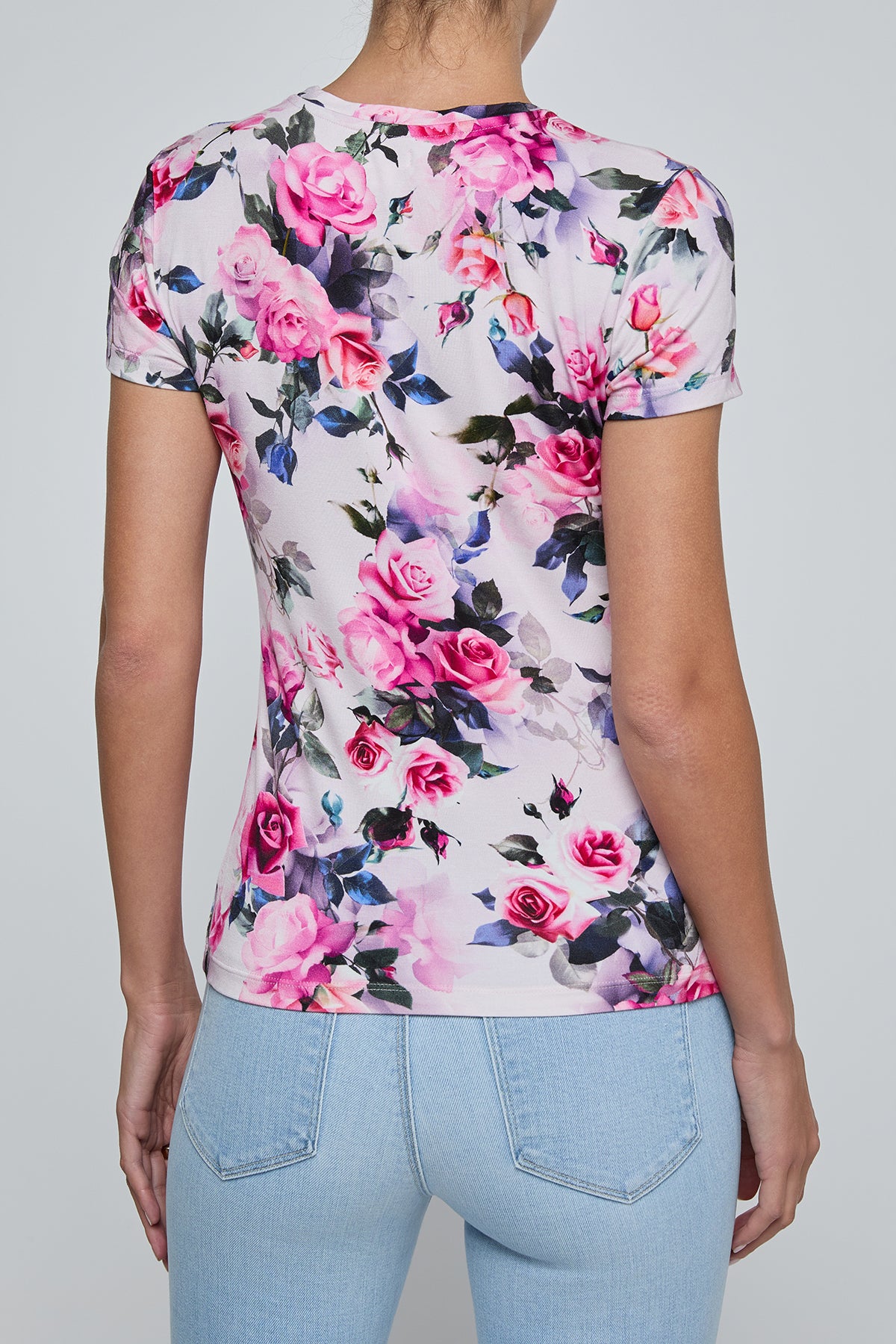 Person wearing a floral t-shirt with pink roses on a plain background