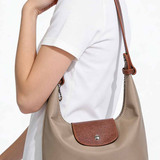Person wearing a beige handbag with brown accents on a white background