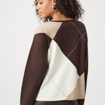 Woman wearing a brown, beige, and white patterned sweater on a white background