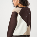Woman wearing a brown, beige, and white patterned sweater on a white background