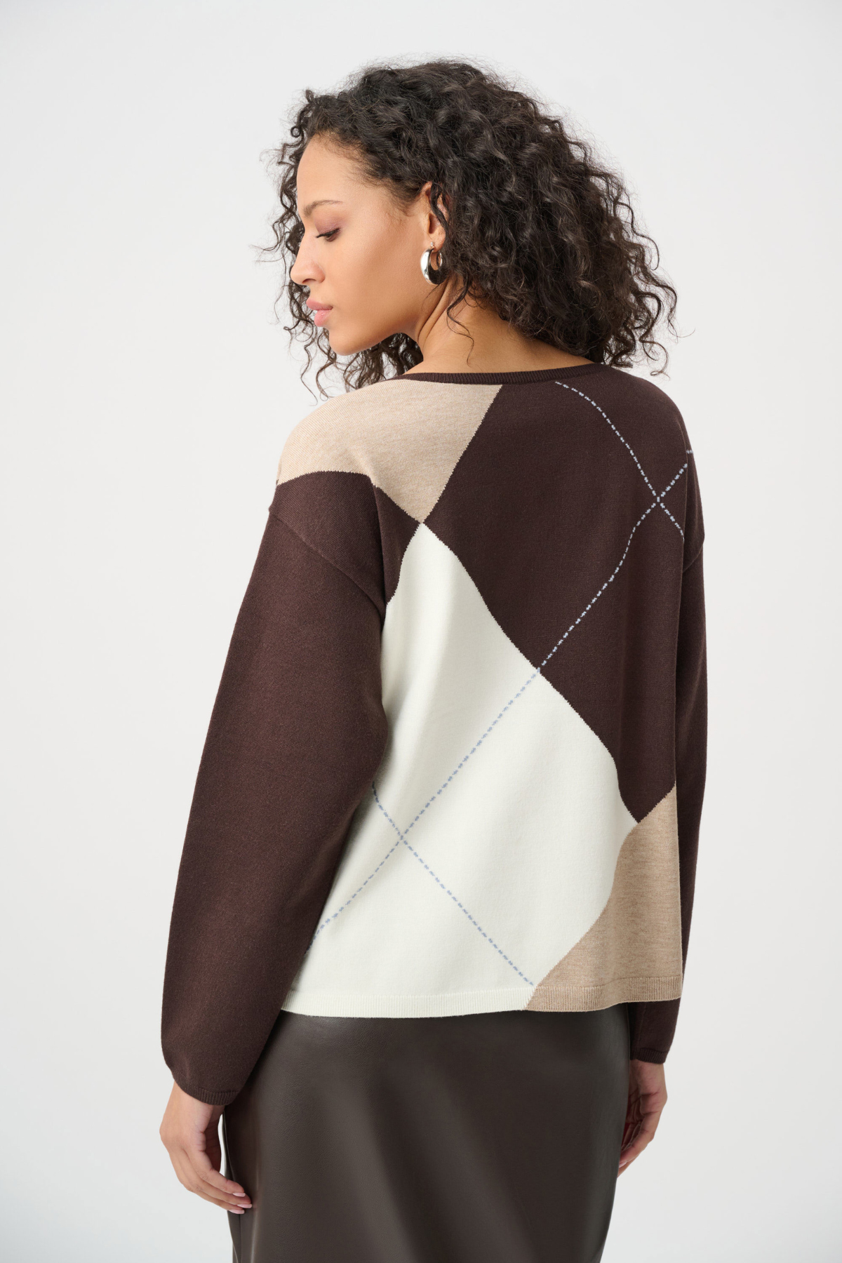 Woman wearing a brown, beige, and white patterned sweater on a white background