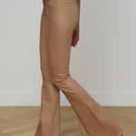 Person wearing beige flared pants on a wooden floor with a white wall background