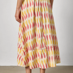 Person wearing a colorful patterned skirt with a plain background