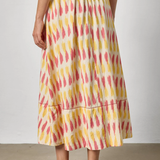 Person wearing a colorful patterned skirt with a plain background