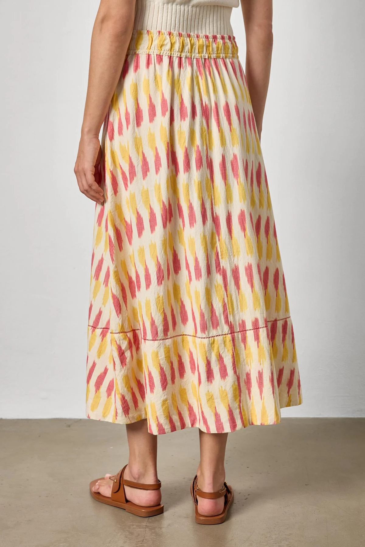 Person wearing a colorful patterned skirt with a plain background