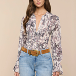 Woman wearing a floral blouse and blue jeans with a beige background