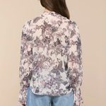 Person wearing a floral blouse and blue jeans on a beige background